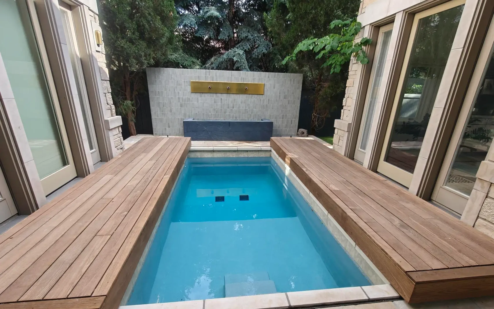 Genuine S-LIDE wood-finish sliding deck covers flanking an elegant courtyard pool